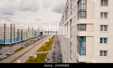 Luftaufnahme eines modernen Wohngebäudes und einer Stadtstraße mit fahrenden Autos. Video. Neu gebaute bunte Häuser auf bewölktem Himmel Hintergrund Stockfoto