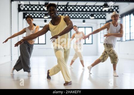 Positiver afro-amerikanischer Mann, der mit seinen Freunden Bewegung des zeitgenössischen Tanzes im Klassenzimmer studiert Stockfoto