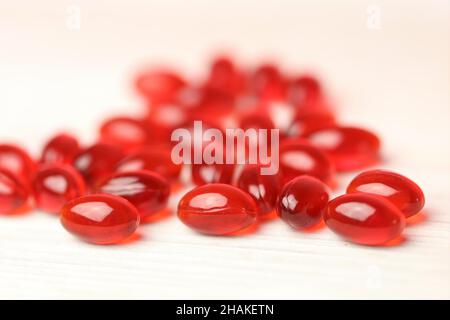 Krillöl rote Gelatine Kapseln auf einem weißen Holzhintergrund .Omega-Fettsäuren.natürliche Nahrungsergänzungsmittel und Vitamin Stockfoto
