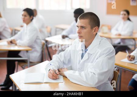 Konzentrierter Medizinstudent für Erwachsene, der während des Auffrischungskurses aufmerksam der Vorlesung im Klassenzimmer zuhört Stockfoto