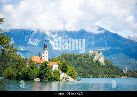 Kirche der Heiligen Maria auf der kleinen Insel am Bleder See vor dem Berghintergrund in Slowenien Stockfoto