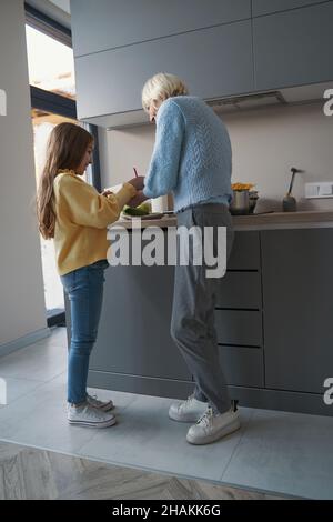 Kleine Enkelin und Oma arbeiten zusammen in der Küche Stockfoto