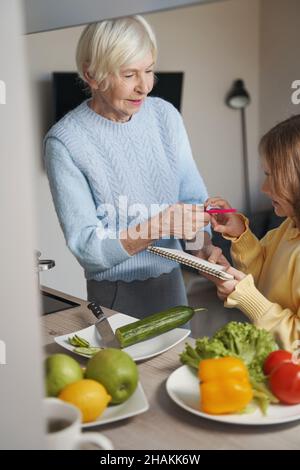 Liebevolle Großmutter hilft einem Kind bei den Hausaufgaben Stockfoto