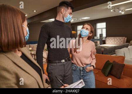 Zwei Kunden in Gesichtsbezügen und Verkäufer Stockfoto