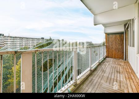 Langer, enger Balkon mit Holzboden und Mesh in der Nähe der Geländer Stockfoto