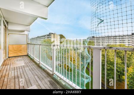 Langer, enger Balkon mit Holzboden und Mesh in der Nähe der Geländer Stockfoto