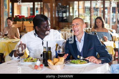 Zwei fröhliche männliche Freunde beim Abendessen im Restaurant Stockfoto