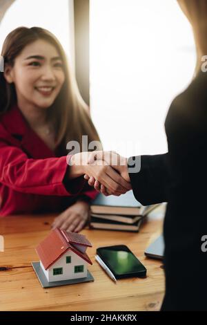 Immobilienmakler und Kunde schütteln Hände nach Abschluss des Vertrages nach über Hausversicherung und Investitionsdarlehen Stockfoto