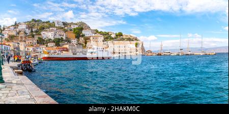 Panoramablick auf den kleinen Hafen und Hafen auf der griechischen Insel Hydra, Griechenland, mit Geschäften, Cafés und Booten im Meer. Stockfoto