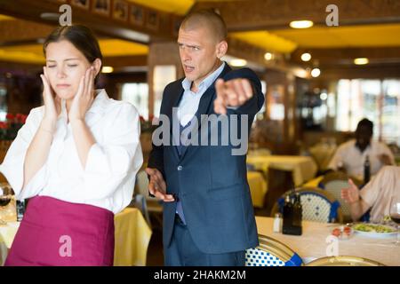 Der Besitzer des Restaurants schreit den schuldig Kellner an Stockfoto