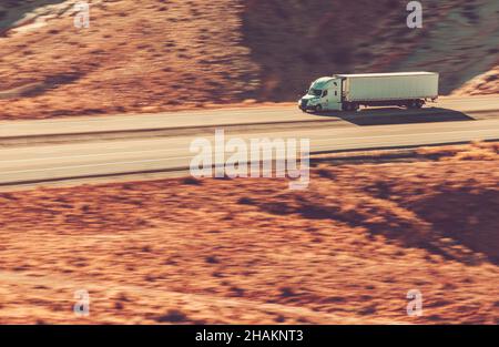 Speeding Modern Semi Trailer Truck auf der Interstate Highway 70, Utah State USA. Felsformationen Landschaft. Stockfoto