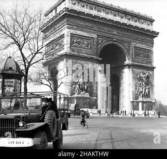 Paris Arc de triomphe mit US Jeep und Navy Personal, 1945. Zu sehen ist der neoklassische Triumphbogen (1836) und der kreisförmige Place de l Etoile, der von der Avenue Marceau gegen Ende des Zweiten Weltkriegs aus aufgenommen wurde Der Jeep sitzt mit drei amerikanischen Matrosen, die auf den vierten warten, der aus dem Fahrzeug kommt und das Foto macht. Auf der Fahrbahn befinden sich ein Radfahrer und ein Militärfahrzeug. Ein Mann zieht einen primitiven Zweirad-Wagen in die Fahrbahn. Auf dem Foto sind zahlreiche Besucher unter dem Arc zu sehen. Ein Kiosk wirbt für die Loterie Nationale. Alte Straßenlaternen sind zu sehen. Stockfoto