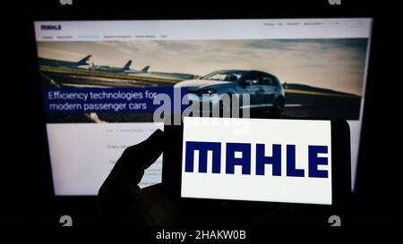 Person, die das Smartphone mit dem Logo des deutschen Automobilzulieferers MAHLE GmbH auf dem Bildschirm vor der Website hält. Konzentrieren Sie sich auf die Telefonanzeige. Stockfoto