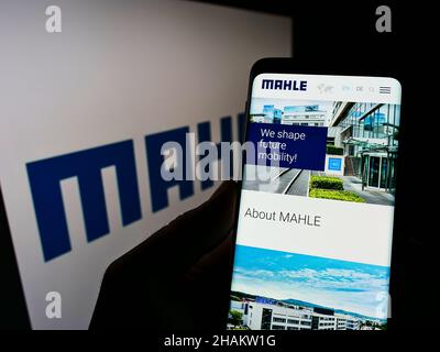 Person, die Mobiltelefon mit der Webseite des deutschen Automobilzulieferers MAHLE GmbH auf dem Bildschirm vor dem Logo hält. Konzentrieren Sie sich auf die Mitte des Telefondisplays. Stockfoto