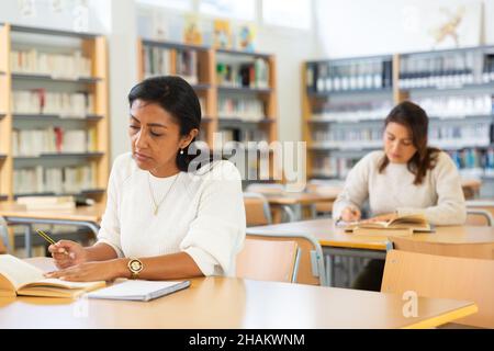 Fokussierte Erwachsene Latina studieren in der Universitätsbibliothek Stockfoto