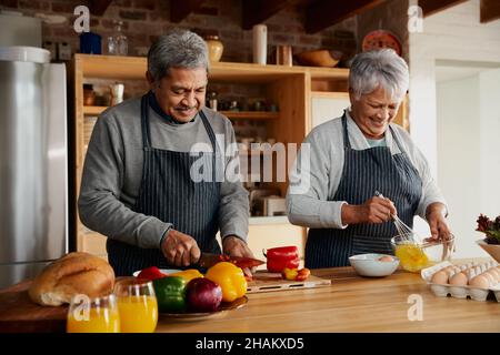 Glückliches multikulturelles älteres Paar, das in der modernen Küche Essen zubereitet. Gesunder Lebensstil im Ruhestand zu Hause. Stockfoto