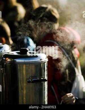 Bild mit geringer Schärfentiefe (selektiver Fokus) und Dampf aus einem tragbaren Wasserkocher für Kaffee und Tee. Stockfoto