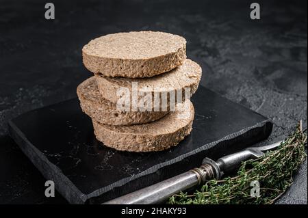 Ungekochte Burger-Koteletts aus Fleisch auf pflanzlicher Basis, rohe vegane Patties. Schwarzer Hintergrund. Draufsicht Stockfoto