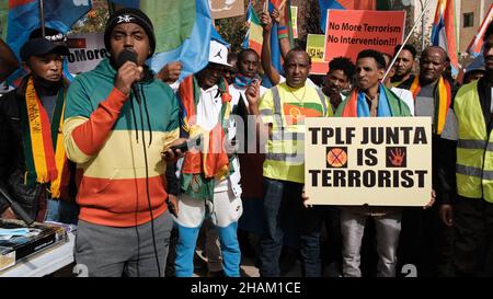 Jerusalem, Israel. 13h Dez 2021. Ein Protestierender hält ein Plakat mit der Aufschrift „TPLF ist terroristisch“, während andere Slogans während eines Protests von äthiopischen Juden und Mitgliedern der eritreischen Migrantengemeinschaft gegen die Politik der Vereinigten Staaten gegenüber dem Tigray-Konflikt in Äthiopien am 13. Dezember 2021 vor der US-Botschaft in Jerusalem, Israel, rufen. Kredit: Eddie Gerald/Alamy Live Nachrichten Stockfoto