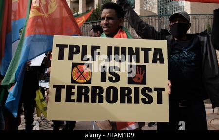 Jerusalem, Israel. 13h Dez 2021. Ein Protestierender hält ein Plakat mit der Aufschrift „TPLF ist terroristisch“ während eines Protestes, der von äthiopischen Juden und Mitgliedern der eritreischen Migrantengemeinschaft gegen die Politik der Vereinigten Staaten gegenüber dem Tigray-Konflikt in Äthiopien am 13. Dezember 2021 vor der US-Botschaft in Jerusalem, Israel, abgehalten wurde. Kredit: Eddie Gerald/Alamy Live Nachrichten Stockfoto