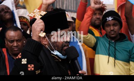 Jerusalem, Israel. 13h Dez 2021. Ein Mitglied der äthiopisch-orthodoxen Kirche spricht während eines Protestes von äthiopischen Juden und Mitgliedern der eritreischen Migrantengemeinschaft in Israel gegen die Politik der Vereinigten Staaten gegenüber dem Tigray-Konflikt Äthiopiens vor der US-Botschaft am 13. Dezember 2021 in Jerusalem, Israel. Kredit: Eddie Gerald/Alamy Live Nachrichten Stockfoto