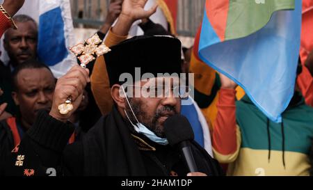 Jerusalem, Israel. 13h Dez 2021. Ein Mitglied der äthiopisch-orthodoxen Kirche spricht während eines Protestes von äthiopischen Juden und Mitgliedern der eritreischen Migrantengemeinschaft in Israel gegen die Politik der Vereinigten Staaten gegenüber dem Tigray-Konflikt Äthiopiens vor der US-Botschaft am 13. Dezember 2021 in Jerusalem, Israel. Kredit: Eddie Gerald/Alamy Live Nachrichten Stockfoto