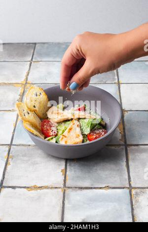 Gesunde Bio-Huhn Caesar Salat mit gegrilltem Huhn und Croutons Frau Hand Stockfoto