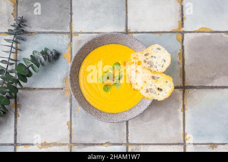 Kürbis- und Karottencremesuppe auf weißem Fliesenhintergrund mit Croutons. Draufsicht. Stockfoto