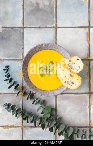 Kürbis- und Karottencremesuppe auf weißem Fliesenhintergrund mit Croutons. Draufsicht. Stockfoto