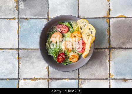 Caesar Salat mit Garnelen und Parmesan auf Fliesengrund Stockfoto