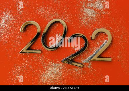 2022 Neujahrs- und Weihnachtsfeier. Komposition mit Zahlen auf orangefarbenem Hintergrund Stockfoto