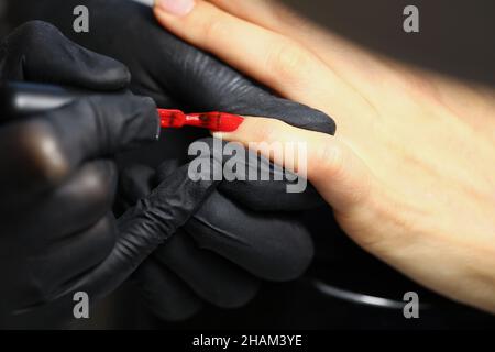 Professionelle Salonarbeiter decken Kunden Nägel mit roter Farbpolitur ab Stockfoto