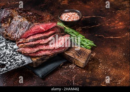 Gebratenes, hängendes, zartes oder in Scheiben geschnittenes Rindersteak auf einem Fleischbrett mit Hackschnitzel. Dunkler Hintergrund. Draufsicht. Speicherplatz kopieren Stockfoto