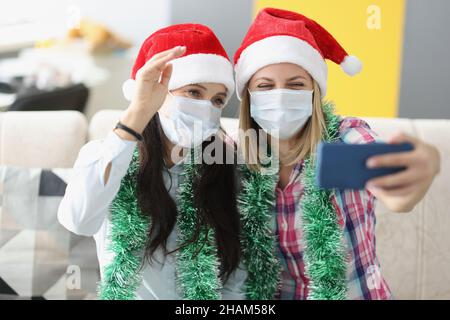 Niedliche beste Freunde nehmen Spaß Selfie in Gesichtsmasken auf dem Smartphone und lachen Stockfoto