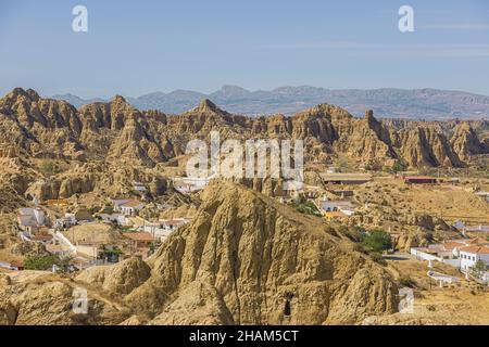 Das Höhlenhausviertel mit den Siedlungen der Troglodyten zum Schutz vor der Hitze in Guadix. Die Hitze verursacht eine verschwommene Sicht auf die fernen Berge. Stockfoto