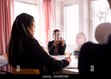 Geschäftsfrauen diskutieren während des Meetings über den Roboter-Sprachassistenten Stockfoto