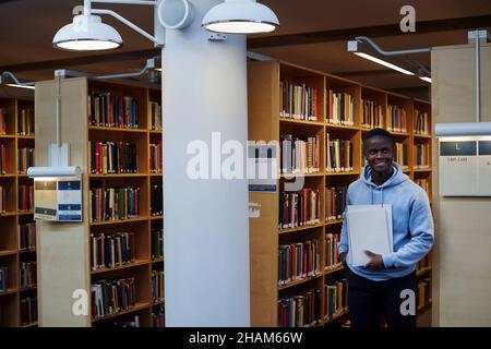 Junger männlicher Student in der Bibliothek Stockfoto