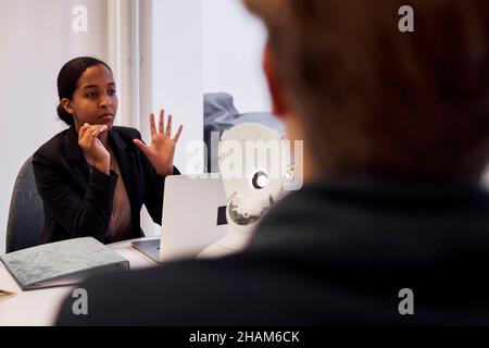 Geschäftsleute diskutieren während des Meetings über den Roboter-Sprachassistenten Stockfoto