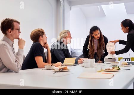 Geschäftsleute diskutieren während des Meetings über den Roboter-Sprachassistenten Stockfoto