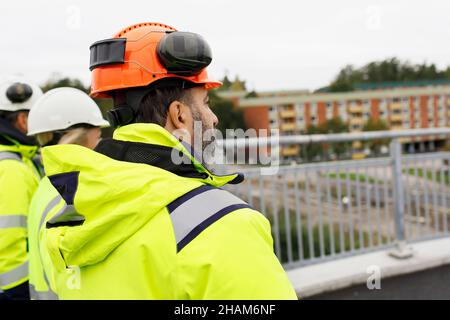 Ingenieure in reflektierender Kleidung gehen auf der Brücke Stockfoto