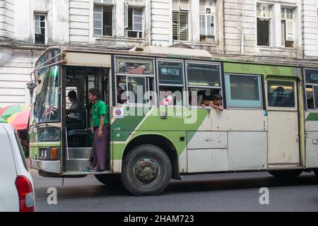 YANGON, MYANMAR - 4. JANUAR 2016: Lokale Busse fahren am 4. Januar 2016 auf den Straßen der Innenstadt von Yangon, Myanmar Stockfoto