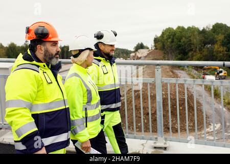 Ingenieure in reflektierender Kleidung gehen auf der Brücke Stockfoto