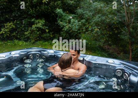 Junges Paar küsst im Jacuzzi Stockfoto