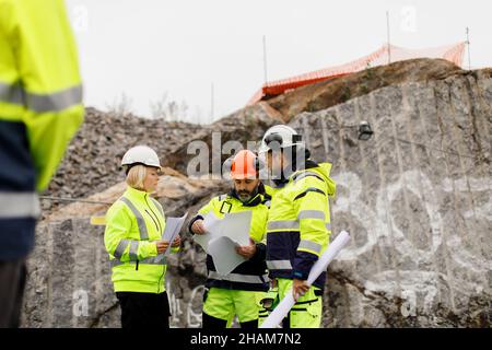 Ingenieure in reflektierender Kleidung diskutieren Pläne Stockfoto