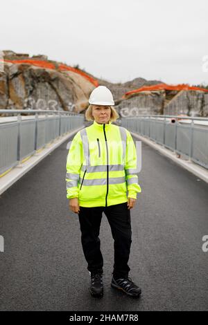 Porträt einer Ingenieurin in reflektierender Kleidung, die auf einer Brücke steht Stockfoto