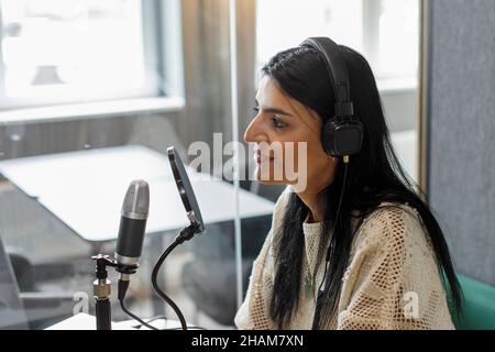 Lächelnde Frau beim Podcast Stockfoto