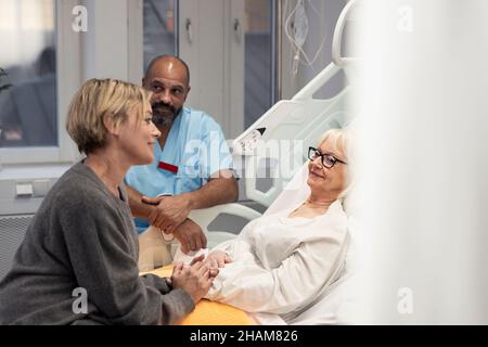 Erwachsene Tochter besucht Mutter im Krankenhaus Stockfoto