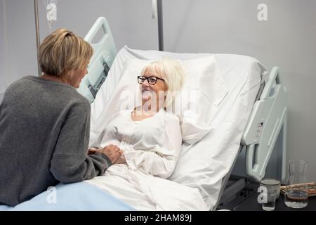 Erwachsene Tochter besucht Mutter im Krankenhaus Stockfoto