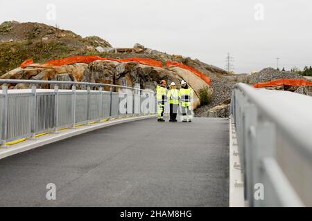 Ingenieure in reflektierender Kleidung gehen auf der Brücke Stockfoto