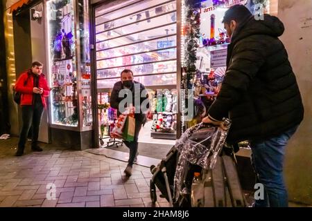 Amsterdam, Niederlande, 13-12-2021. 5:09 Uhr - der letzte Kunde verlässt einen Laden unter halb geschlossenen Einkaufstüren. Das niederländische Kabinett wird voraussichtlich eine Verlängerung der „Abendsperre“ in die Wege führen, was bedeutet, dass die meisten Unternehmen ab 5 Uhr geschlossen sind. Die Maßnahmen, die jetzt bis zum 19th. dezember eingeführt sind, werden wahrscheinlich bis Anfang Januar 2022 länger in Kraft bleiben. Am Dienstagabend dez. 14 werden der scheidende Premierminister Mark Rutte und der Gesundheitsminister Hugo de Jonge eine Pressekonferenz geben. Kredit: Steppeland/Alamy Live Nachrichten Stockfoto